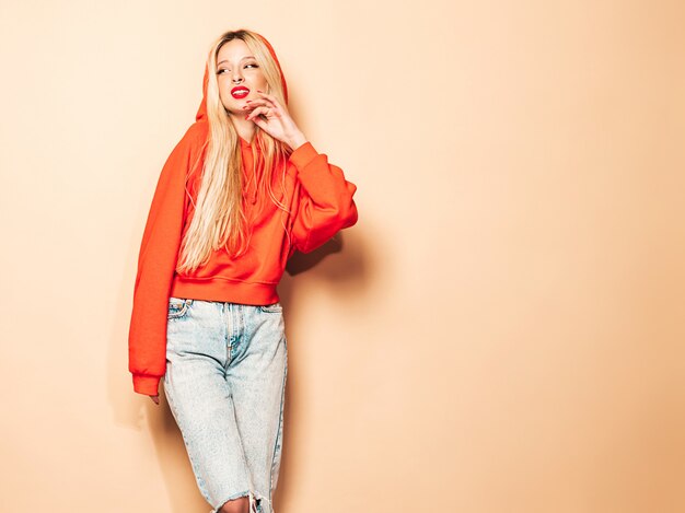 Portrait of young beautiful hipster bad girl in trendy red  hoodie and earring in her nose.  Positive model