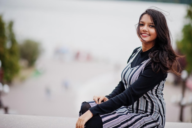 Free photo portrait of young beautiful indian or south asian teenage girl in dress against river