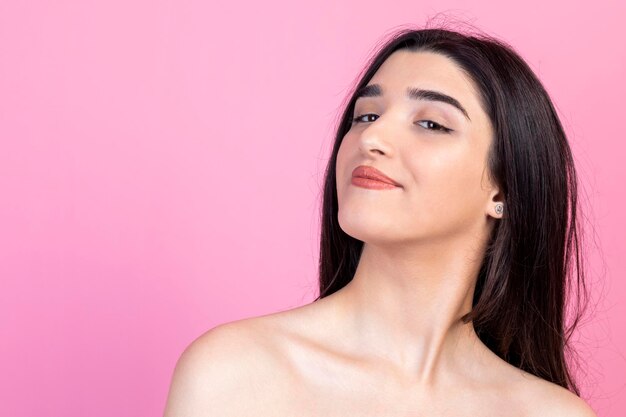 Portrait of young beautiful lady standing on pink background and smiling