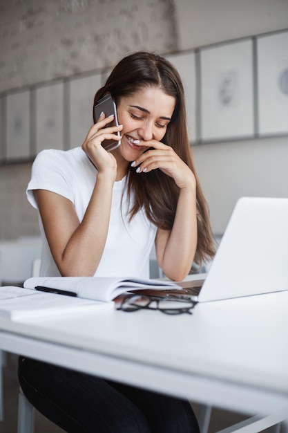 Portrait of young beautiful longhaired caucasian woman laughing talking on smart phone with her girl friend