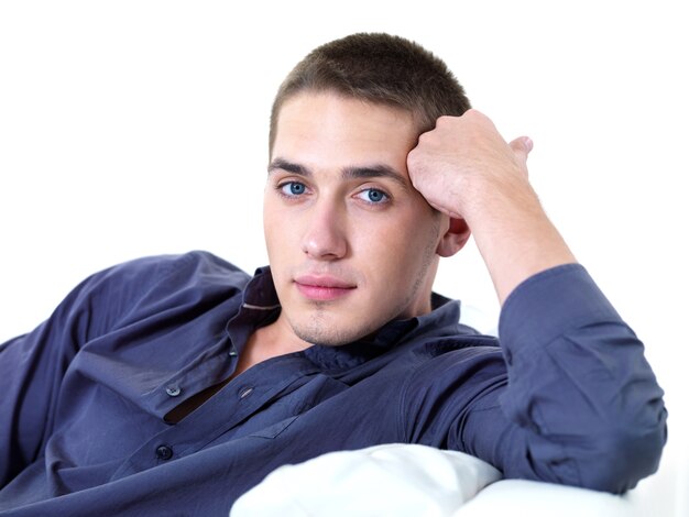 Portrait of young beautiful man lying on the sofa