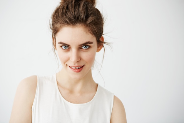 Portrait of young beautiful playful woman with bun biting lip posing.