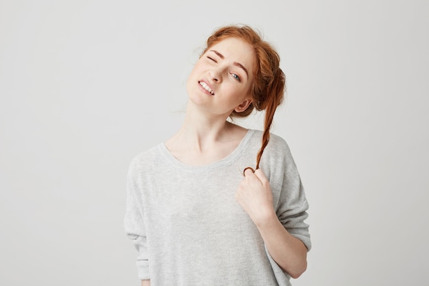 Portrait of young beautiful redhead girl untie bun touching hair .