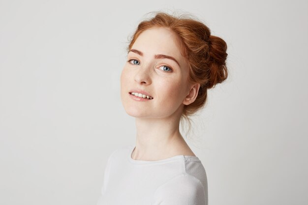 Portrait of young beautiful redhead girl with freckles smiling .