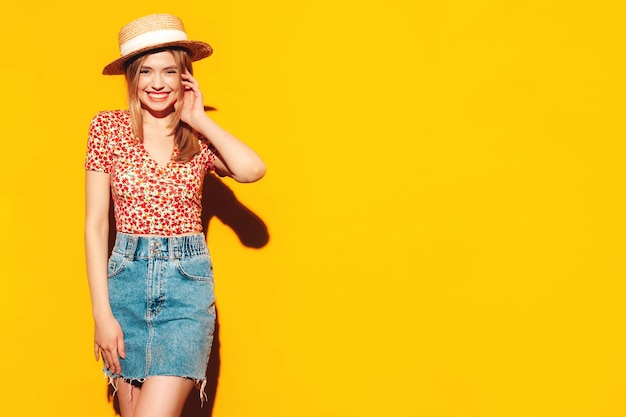 Foto gratuita ritratto di giovane bella donna bionda sorridente in abiti estivi alla moda donna spensierata in posa vicino al muro giallo in studio modello positivo divertendosi al chiuso allegro e felice nel cappello