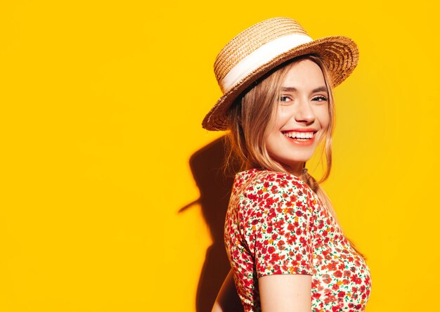 Portrait of young beautiful smiling blond female in trendy summer clothes carefree woman posing near yellow wall in studio Positive model having fun indoors Cheerful and happy In hat