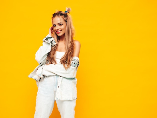 Portrait of young beautiful smiling blond female in trendy summer clothes Sexy carefree woman posing near yellow wall in studio Positive model having fun indoors Cheerful and happy