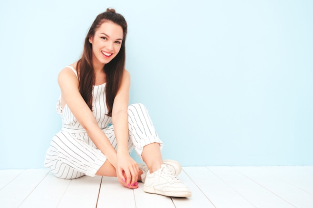 Portrait of young beautiful smiling female in trendy summer hipster overalls clothes