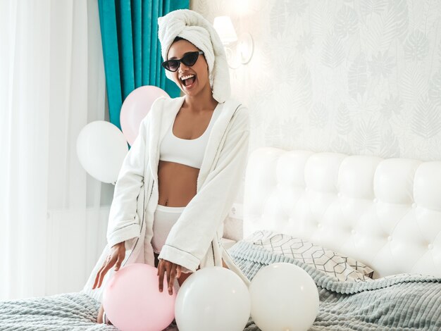 Portrait of young beautiful smiling female in white lingerie and towel on head