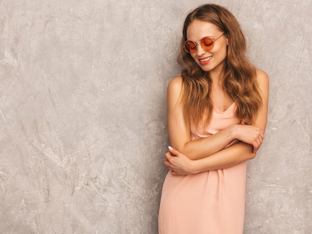 Portrait of young beautiful smiling girl in trendy summer light pink dress. Sexy carefree woman posing. Positive model having fun