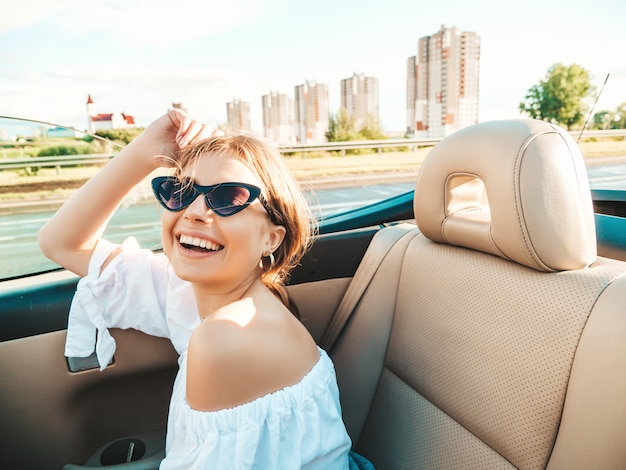 コンバーチブル車で若い美しく笑顔の流行に敏感な女性の肖像画