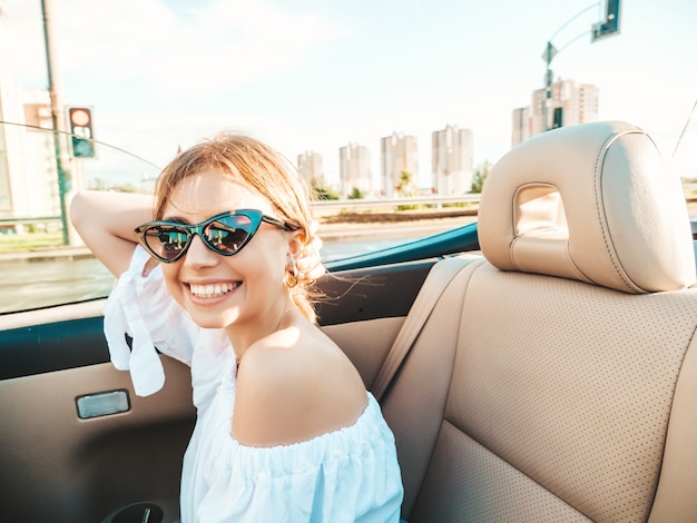 Portrait of young beautiful and smiling hipster female in convertible car
