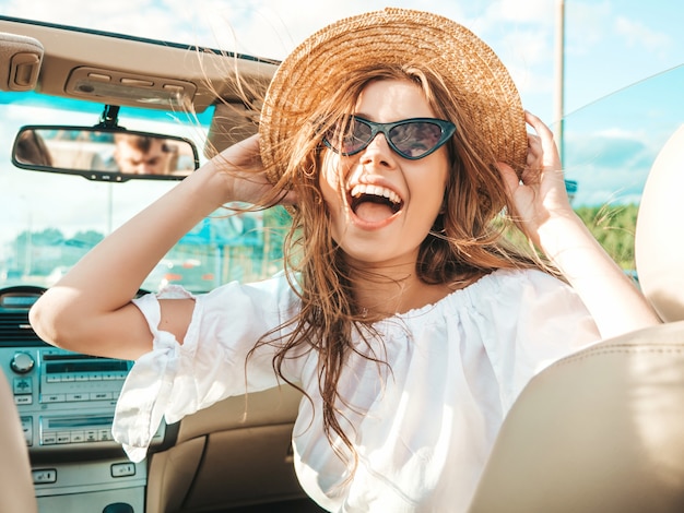 Portrait of young beautiful and smiling hipster girl in convertible car