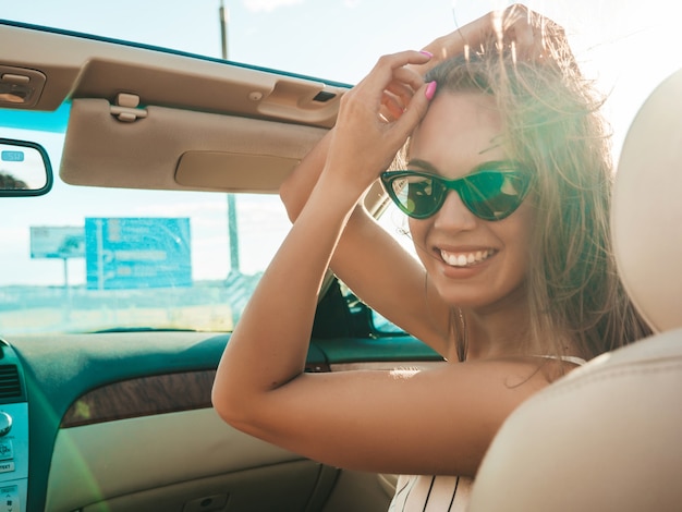 컨버터블 자동차에서 젊고 아름답고 웃는 힙스터 소녀의 초상화