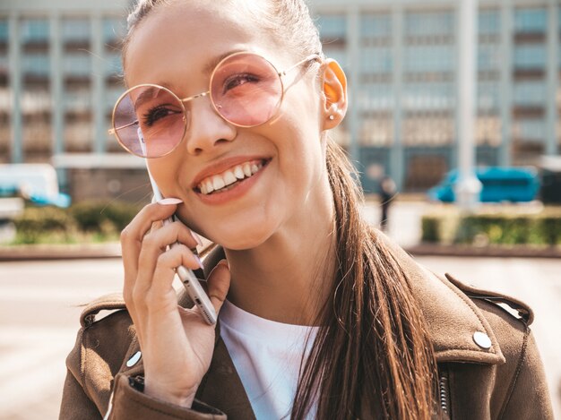 Портрет молодой красивой улыбающейся женщины, говорящей по телефону Модная девушка в повседневной летней одежде Смешная и позитивная женщина позирует на улице