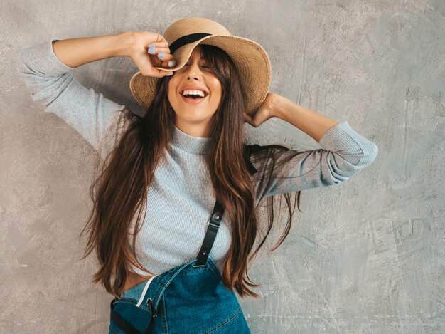 Portrait of Young beautiful smiling woman with closed eyes. Trendy girl in casual summer overalls clothes and hat. 