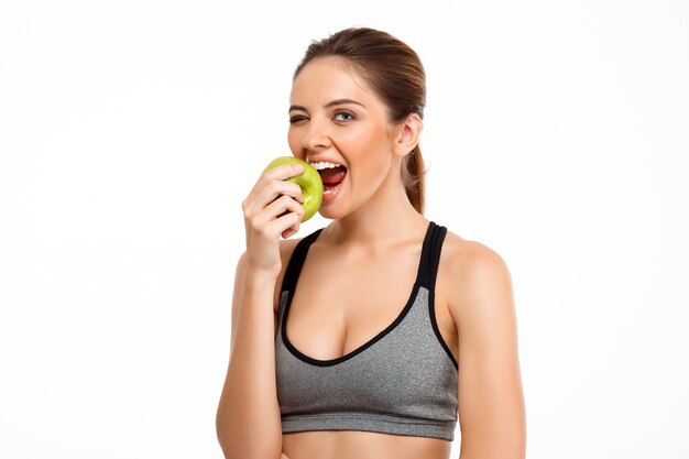 Portrait of young beautiful sportive girl holding apple over white background.