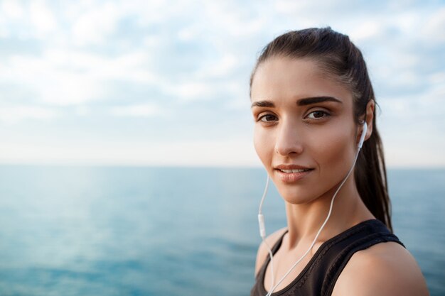 Portrait of young beautiful sportive girl at sunrise over seaside.