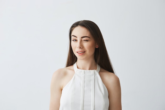 Portrait of young beautiful tender girl in blouse winking smiling .