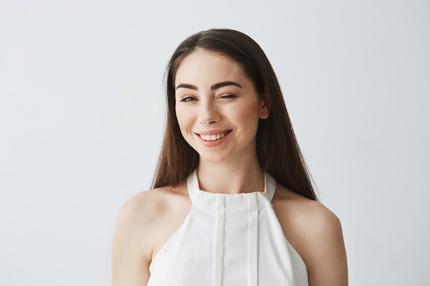 Portrait of young beautiful tender girl in blouse winking smiling .