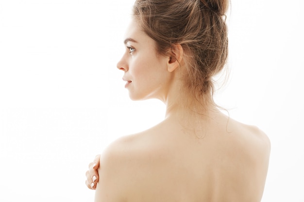 Portrait of young beautiful tender naked woman standing over white background.