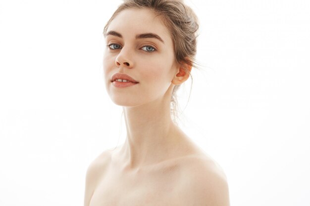 Portrait of young beautiful tender naked woman with bun over white background.