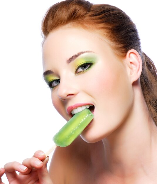Портрет молодой красивой женщины, едящей зеленое сладкое мороженое