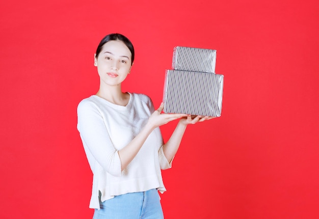 Portrait of young beautiful woman holding gift stack