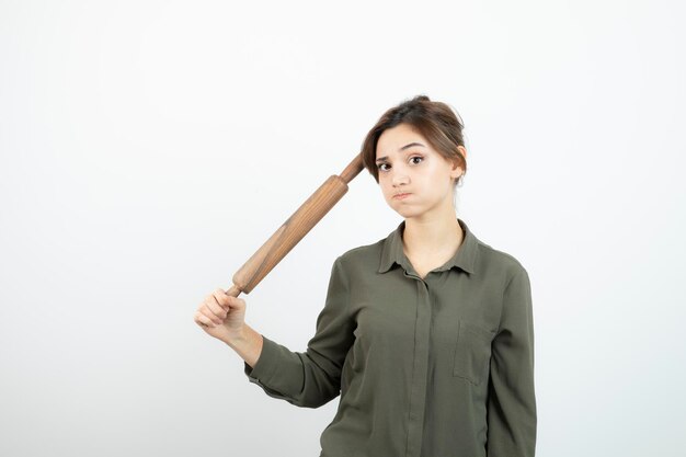 Portrait of young beautiful woman holding wooden rolling pin. High quality photo