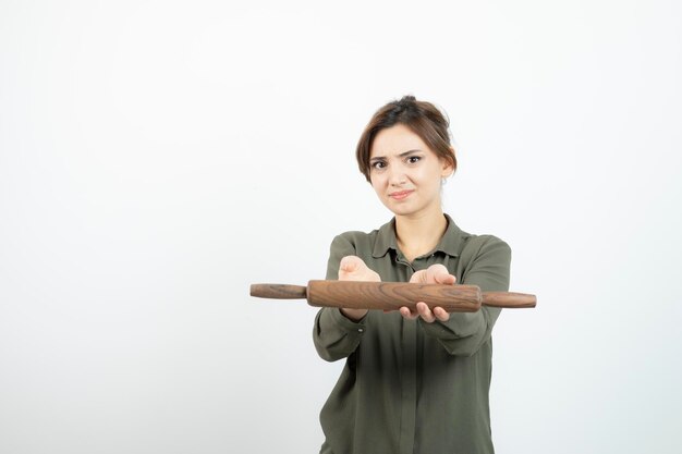 Portrait of young beautiful woman holding wooden rolling pin. High quality photo