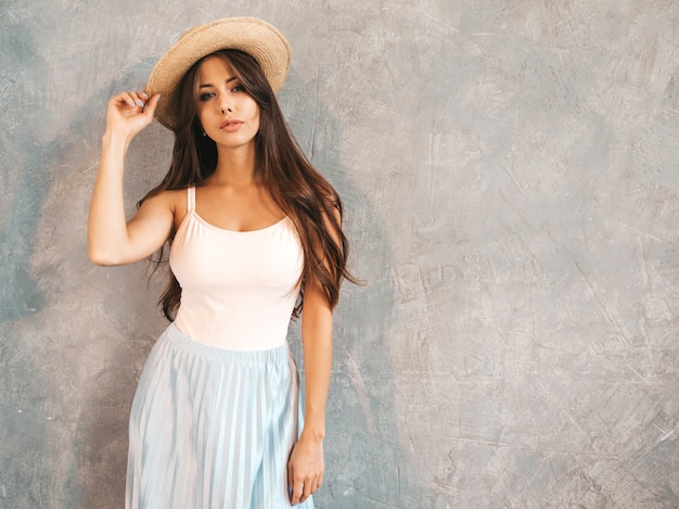 Portrait of Young beautiful woman looking . Trendy girl in casual summer dress and hat.  