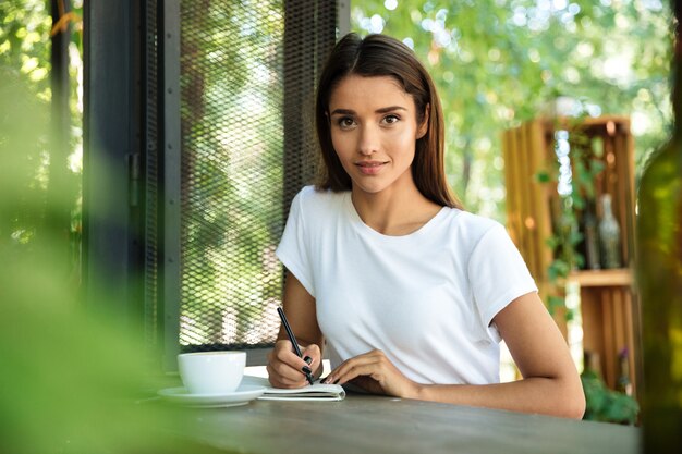 Portrait of a young beautiful woman making notes in a textbook