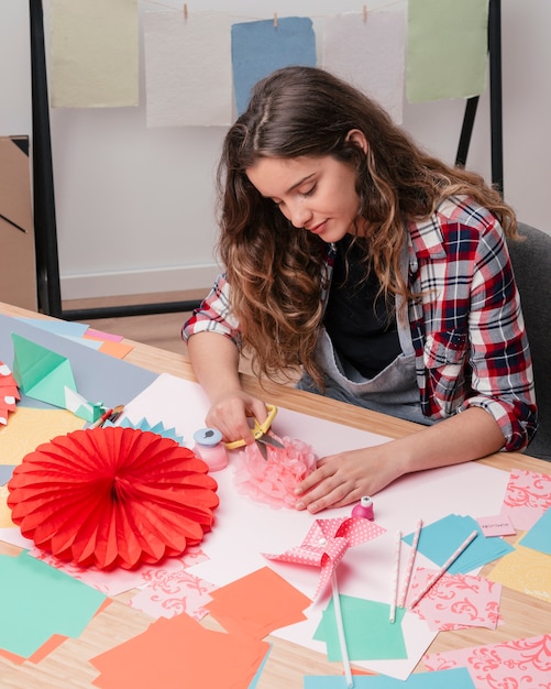 折り紙の紙の花を作る若い美しい女性の肖像画