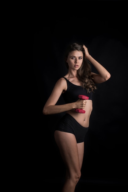 Portrait of young beautiful woman making physical exercises with dumbbells