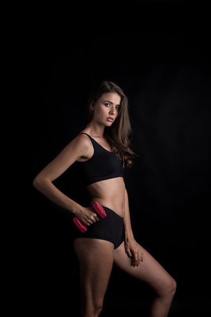 Portrait of young beautiful woman making physical exercises with dumbbells