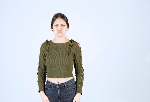 Portrait of a young beautiful woman model standing and posing over white wall.