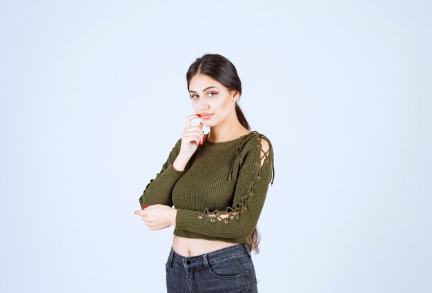 Portrait of a young beautiful woman model standing and posing over white wall.