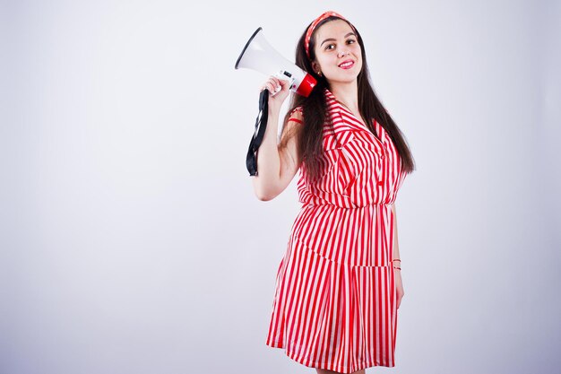 Portrait of a young beautiful woman in red dress talking into megaphone