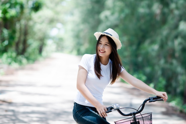 Portrait of young beautiful woman riding a bicycle in a park.