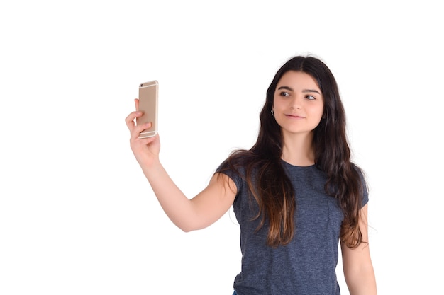 Портрет молодой красивой женщины, делающей селфи со своим мобильным телефоном, изолированным в студии