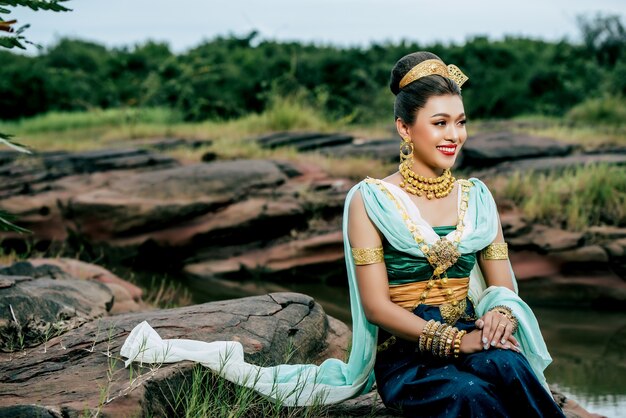 Portrait young beautiful woman wearing in traditional costume with ornament posing in nature in Thailand