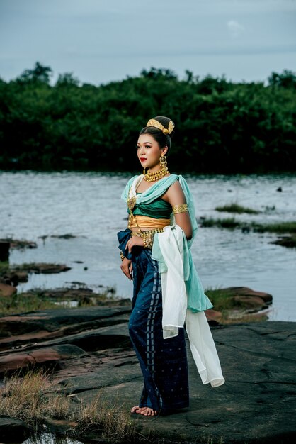 Portrait young beautiful woman wearing in traditional costume with ornament posing in nature in Thailand