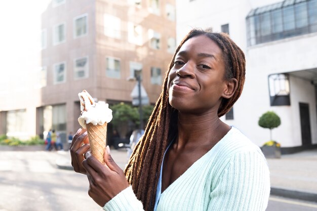 Portrait of young beautiful woman with afro dreadlocks enjoying an ice cream in the city