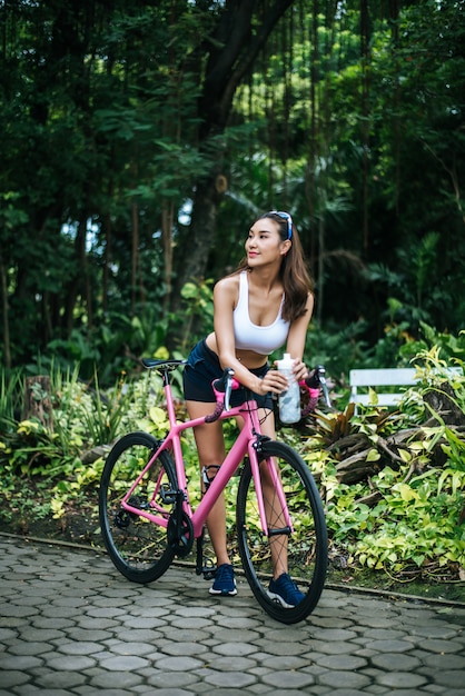 Portrait of young beautiful woman with pink bike in the park. Actractive healthy woman.