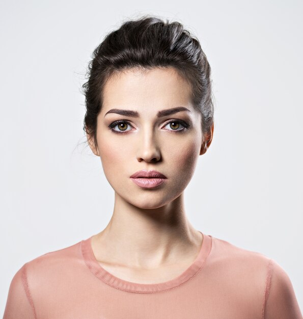 Portrait of an young beautiful  woman with  smoky eyes makeup. Pretty young adult girl posing at studio. Closeup attractive female face.