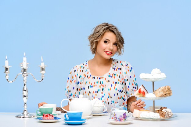 Portrait of young beautiful woman with sweets over blue wall