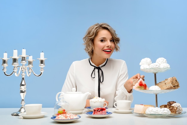 Foto gratuita ritratto di giovane bella donna con i dolci sopra la parete blu