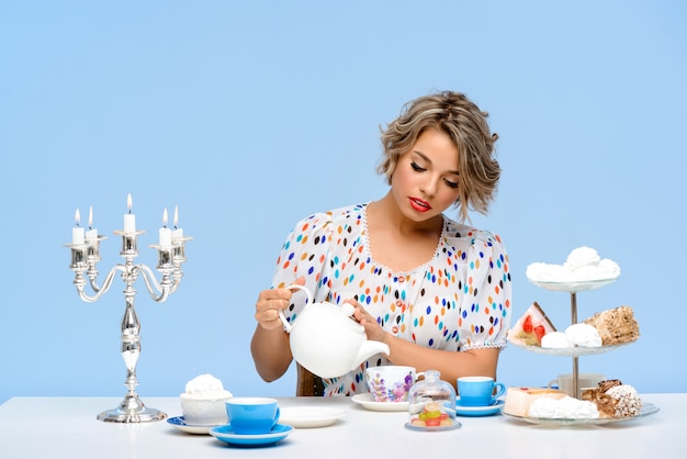 Portrait of young beautiful woman with sweets over blue wall