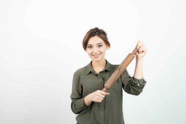 木製の麺棒が立っている若い美しい女性の肖像画。高品質の写真