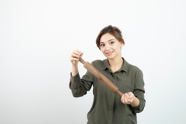 Portrait of young beautiful woman with wooden rolling pin standing. High quality photo